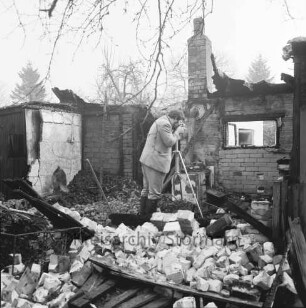Brand: Sieker Landstraße: Behelfsheim: Brandruine: Innenraum: darin Mauerwerk und verbrannte Gegenstände: in der Mitte Brandsachverständiger beim Fotografieren: hinten Bäume