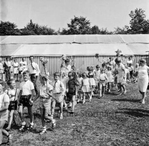 Kindervogelschießen: Festwiese: Festumzug: Klassen mit Blumenstöcken: rechts Lehrerinnen: hinten Zuschauer vorn Festzelt