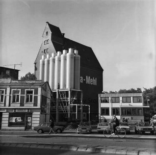 Johannes Ströh Mühlenwerke: Weizenmühle ("Gloria-Mühle"): am Pferdemarkt: Modernisierung: Tankzug-Beladeanlage mit 2 Reihen à 6 Ladezellen vor Fertigstellung: dahinter gemauertes Silo: links Gebäude der ehemaligen Pferdeschlachterei Sengelmann nach Räumung: vorne Straße, Fahrradfahrer, parkende Autos