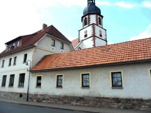 Ansicht von Südosten mit Kirchturm über an den Kirchhof vorgebauten Häusern aus dem Ort