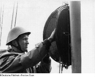 Deutschland . Nationale Volksarmee - Seestreitkräfte. Matrose im Kampfanzug-See mit Stahlhelm an einer Signallaterne (?)