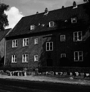 Hebbelstraße: Ausbau: vorn unbefestigte Straße, Stapel mit Gehwegplatten und Mülleimer: dahinter Wohnhäuser der Gemeinnützigen Baugenossenschaft Bad Oldesloe mit Vorgärten