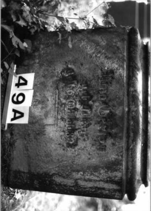 Grabstein 49 (Index: 100081702) Material: Sandstein Zustand: Sockel verwittert Maße HxBxT: 155x57x33 cm Beschreibung: giebelart. Abschl. m. Verdach. , rechteck. Schriftfeld eingetieft, profiliert. Sockel Symbolik: sternchen, gestelztes Rundbogenfries unter Abschluß Steinmetz: A. Metzger: Grabstein 49A