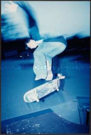 Jugendlicher mit Skateboard im Sprung (Altersgruppe 18-21)