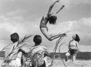 Anja, Tänzerin am Staatsopernballett Hamburg, führt am Strand Tanzübungen vor. Man schaut voller Interesse zu
