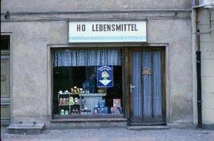 DDR. HO-Lebensmittelgeschäft im Erdgeschoß eines Wohnhauses (1801/1900). Schaufenster mit Plakat "Gesunde Kost für jeden" und Eingangstür