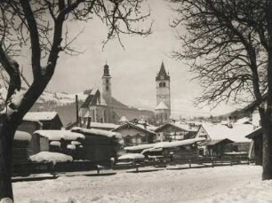 Kitzbühel im Winter.Tirol, Österreich. Verschneite Häuser. Im Hintergrund die Türme der Stadtpfarrkirche "Zum Heiligen Andreas" (links) und der Liebfrauenkirche (rechts)