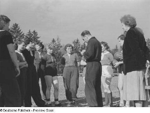 Porträt eines Trainers und mehreren Sportlerinnen auf dem Sportplatz der Sportschule