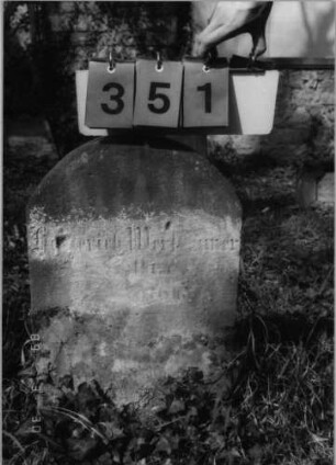Grabstein 351 (Index: 99791747) Material: Sandstein Zustand: stark verwittert mit Textverlust Maße HxBxT: 65x40x13 cm Beschreibung: Stele, Segmentbogenabschluß: Grabstein 351