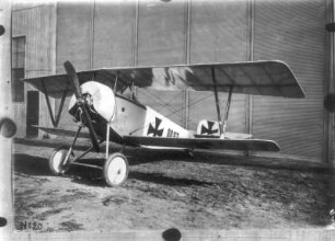 Einsitziges Doppeldecker-Flugzeug 00.27 mit Propellerantrieb (um 1910/1914), eingesetzt von den deutschen Luftstreitkräften im I. Weltkrieg. Schrägansicht von vorn. Fotografie (Nr. 20); an eine Wand gepinnt
