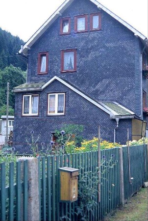 Schieferhaus, Zaun und Garten mit Briefkasten
