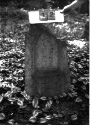 Grabstein 12 (Index: 100105629) Material: Muschelkalk Zustand: Schriftplatte fehlt, Abschluß quer weggebrochen Maße HxBxT: 84x45x21 cm Beschreibung: Stele, Schriftfeld eingetieft: Grabstein 12