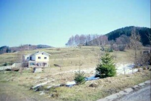 einzelnes neues Haus am Hang, dahinter Ackerterrassen