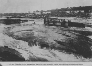 Am Wasserfall : Mehrere Personen stehen mit einem Kanu auf einem Felsen im Wasserfall