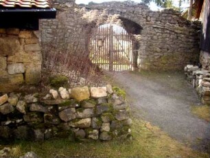 Kirchhof im Westen mit Kirchhofmauer und erhaltenem Außenbogen (einstiges Kammertor zur Feldseite)