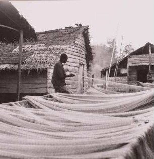Kamerun. Fischer beim Netzflicken vor den Hütten eines Duala-Dorfes, um 1960