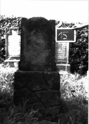 Grabstein 15 (Index: 100100677) Material: Sandstein Zustand: völlig verwittert, Abschluß beschädigt Maße HxBxT: 125x46x18 cm Beschreibung: Stele, Rusticasockel, Abschluß unklar: Grabstein 15