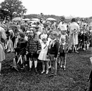 Kindervogelschießen: Festwiese: Festumzug: Schulkinder in Regenjacken und Märchenkostümen: hinten Zuschauer mit Regenschirmen: im Hintergrund Bäume