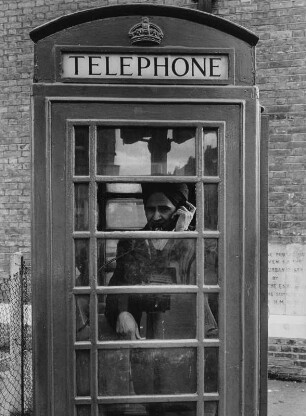 Indischer Mann in einer Telefonzelle, London-Southall