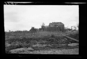 Nicht identifizierbare Ortschaft bei Douai (?) (Dep. Nord, Frankreich): Gebäuderuine neben einem Feld mit Stacheldrahtverhau