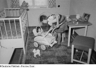 Mädchen mit einem Puppenwagen in einem Kinderzimmer