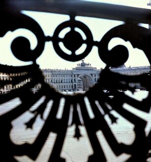 Blick durch eine Gitter auf den Schlossplatz und den Torbogen des Winterpalais