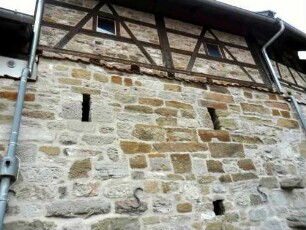 Evangelische Pfarrkirche - Ansicht im Westen (von Ortsseite) mit Kirchhofmauer (Werksteine im Mauersteinverband) sowie erhaltenen Schie0scharten (aus den Gaden heraus) und Fachwerk-Aufsatz