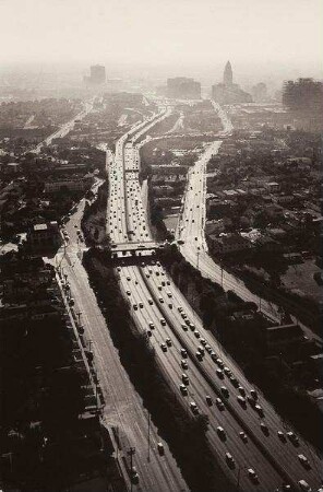 Luftaufnahme eines Highway mit Stadtsilhouette im Hintergrund