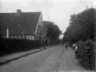spielende Kinder auf einer Straße, links Fachwerkhaus