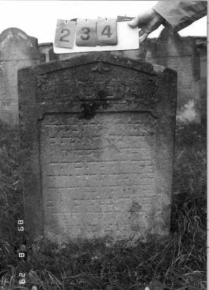 Grabstein 234 (Index: 100107577) Material: heller Sandstein Zustand: stark verwittert, großer Textverlust Maße HxBxT: 93x65x14 cm Beschreibung: Stele mit flachem Giebelabschluß, Schriftfeld rechteckig eingetieft: Grabstein 234