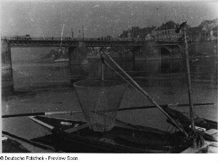 Meißen. Fischerboot mit Senknetz am Ausleger. Blick vom linken Elbufer auf Straßenbrücke und Bebauung am rechten Ufer