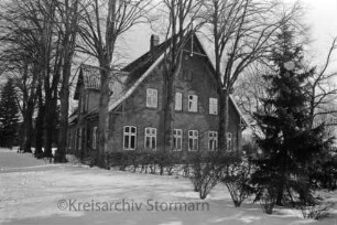 Bauernhaus: davor Hecke und Bäume: Winter