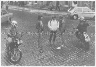 Jungs fahren mit Motorrädern um Mädchen herum (Sonderthema: Mädchen sehen Jungen - Jungen sehen Mädchen)