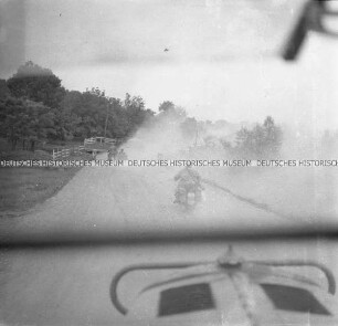 Deutsche Soldaten auf Motorrädern auf einer staubigen Landstraße, aus einem LKW fotografiert