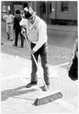 Joseph Beuys beim Fegen der Straße - Aktion "Ausfegen" nach der Mai-Kundgebung
