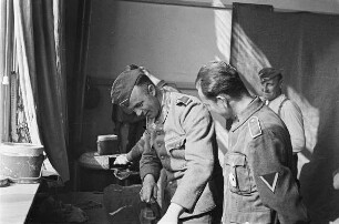Zweiter Weltkrieg. Niederlande unter deutscher Besatzung. Deutsche Wehrmachtsangehörige in ihrer Unterkunft, einer beim Bügeln (wohl bei Den Haag)
