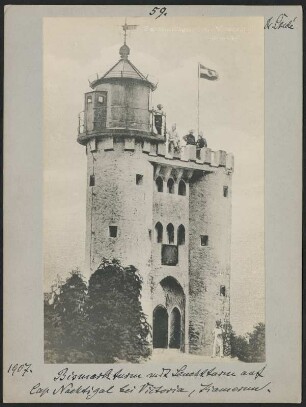 Bismarckturm/Leuchtturm Cap Nachtigal bei Limbé, Kamerun : Verbreitetes Ansichtskartenmotiv des Bismarckturms am Cap Nachtigal, umgebaut in Leuchtturm 1903, mit der gehissten Fahne des Deutschen Kaiserreichs, als Staffage befinden sich Personen auf dem Dachplateau sowie rechts des Eingangs; fotografische Reproduktion einer gedruckten Vorlage