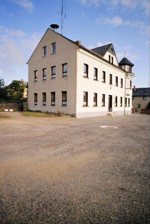 Schulgebäude mit großem Dacherker, an hinterer Ecke Turm
