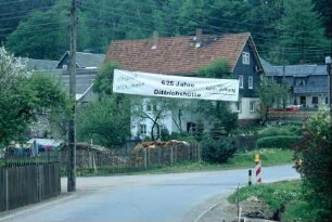 Ortseingang mit Staketenzäunen und Gärten, Transparent "625 Jahre Dittrichshütte"