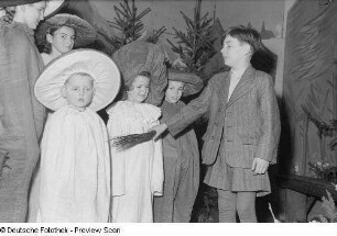 Eine Gruppe von Kindern, teils als Pilze verkleidet, stehen vor einer Waldkulisse in der Aufführung eines Märchens bei der Weihnachtsfeier des Verlags Volk und Wissen