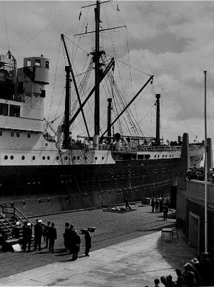 Cuxhaven. Das am 12.03.1927 in Dienst gestellte Passagierschiff "New York" der Hapag liegt am Passagierkai zur Abfahrt nach Amerika bereit. An der Bordtreppe stehen Besatzungsmitglieder zum Empfang von Passagieren. Zuschauer nehmen an der Einschiffung der Passagiere und der Verbachiffung des Schiffes teil.