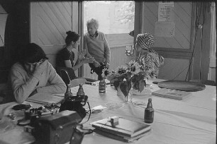 Höfgen. Akt-Pleinair 1979. Die Fotografen Eva Mahn, Günter Rössler und andere Teilnehmer im Gespräch, am Tisch sitzend ein Fotomodell mit Turban