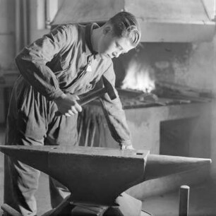 Lehrling von Borgward beim Schmieden am Amboss mit Hammer und Zange