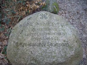Ahrensburg: Burg Arnesvelde: Findling mit Beschriftung zum archäologischen Denkmal
