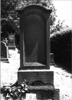 Grabstein 163 (Index: 100085425) Maße HxBxT: 160x51x22 cm Beschreibung: Stele, getrepp. Sockel, eingezog. Rundbogenabschl. m. Verdach. , Schriftfeld eingetieft: Grabstein 163