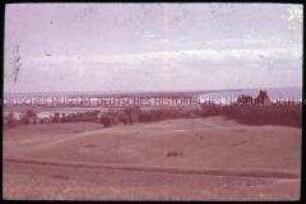 Blick von einer Holzbrücke auf das Flussufer