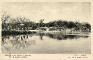 Eine Frau mit Sonnenschirm und ein Mann auf einer Insel im Fluss Kunene