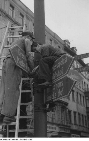 Arbeiter beim Anbringen von Hinweisschildern für die Herbstmesse 1953
