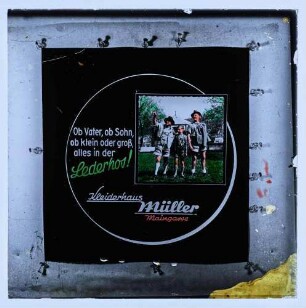 Werbung des Kleiderhauses Müller in der Maingasse mit Slogan "Ob Vater, ob Sohn, ob klein oder groß, alles in der Lederhos!"