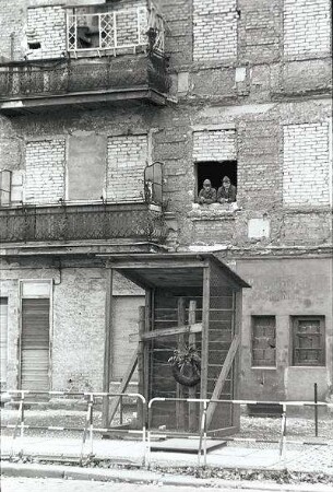 Berlin: Die Pressefahrt; Bernauer Straße; zugemauertes Haus; zwei Soldaten am Fenster; Flüchtlingsgrab